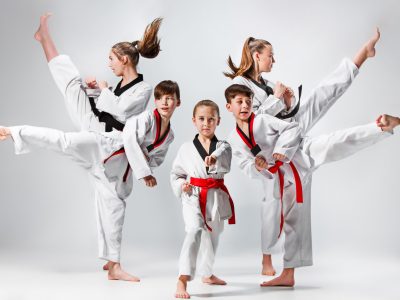 The studio shot of group of kids training karate martial arts on gray backlground